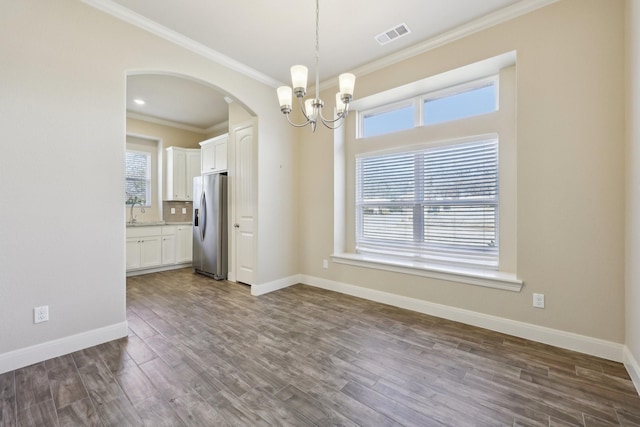 unfurnished dining area with dark wood-type flooring, crown molding, a chandelier, and sink