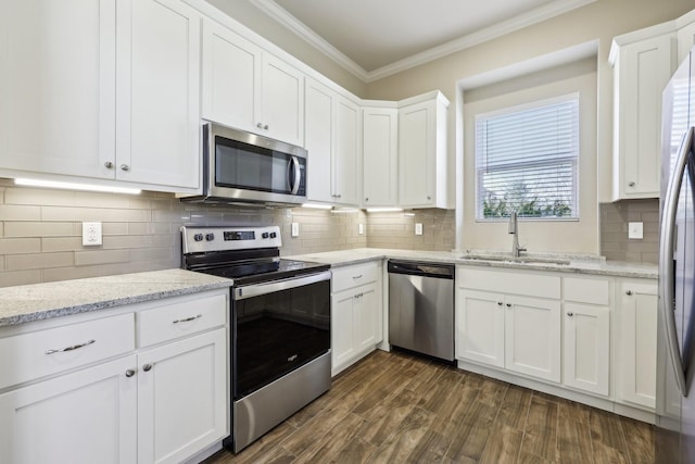 kitchen with appliances with stainless steel finishes, sink, white cabinets, crown molding, and dark wood-type flooring