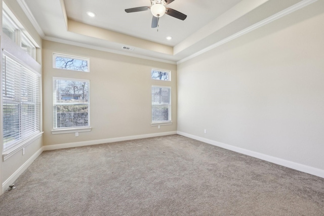 carpeted empty room featuring ornamental molding, ceiling fan, and a tray ceiling