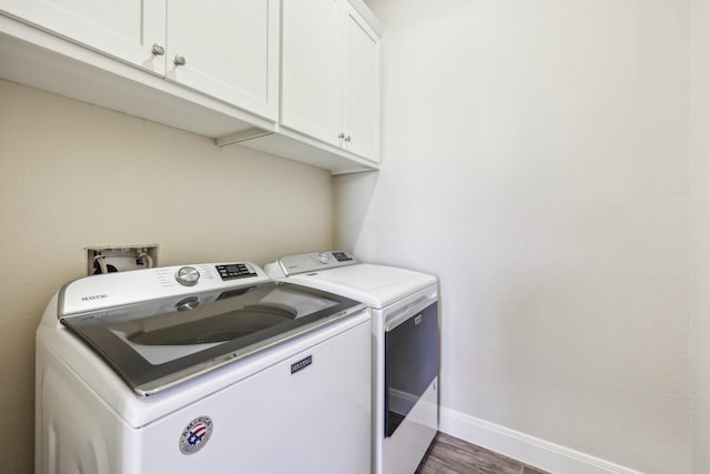 washroom with cabinets, washing machine and dryer, and dark wood-type flooring