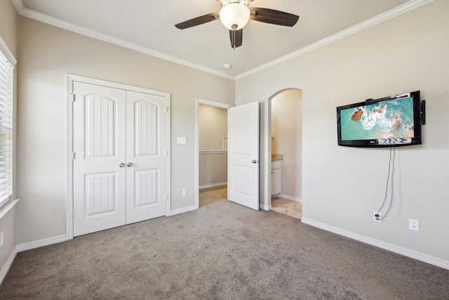 unfurnished bedroom with crown molding, a closet, ceiling fan, and light carpet