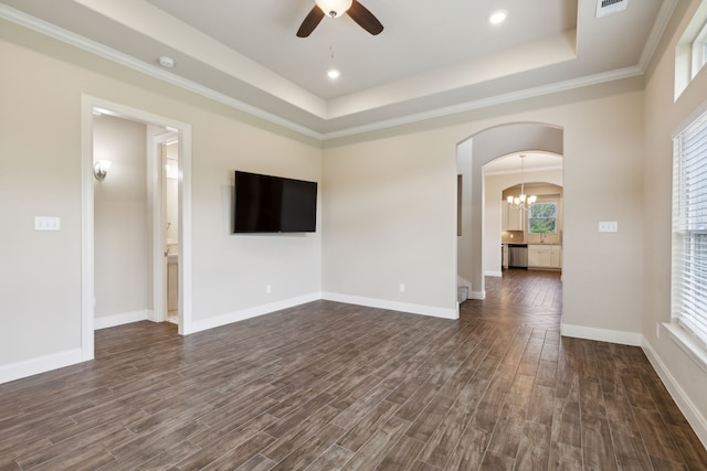 unfurnished living room featuring dark hardwood / wood-style floors, a raised ceiling, ornamental molding, and ceiling fan with notable chandelier