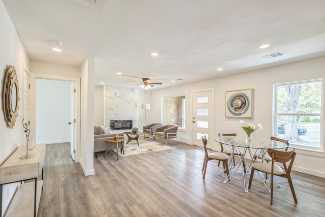 dining room featuring wood-type flooring, a fireplace, and ceiling fan