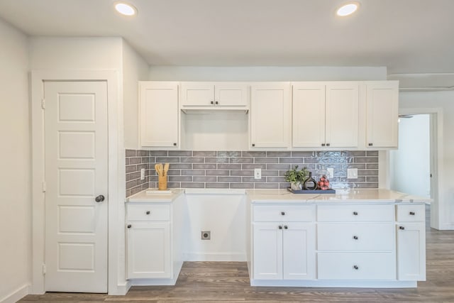 kitchen with backsplash, wood-type flooring, and white cabinetry