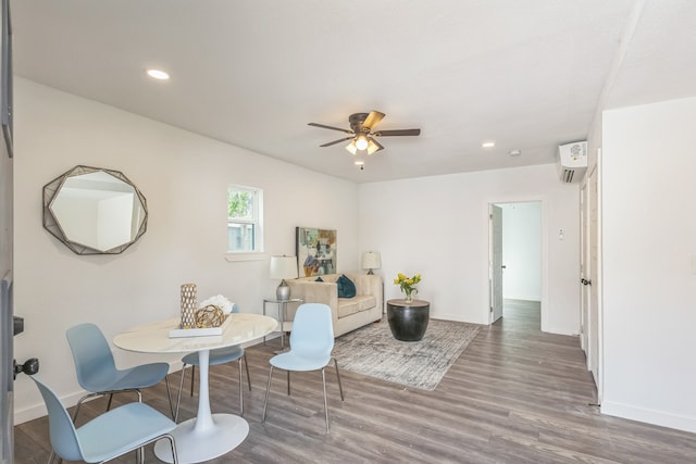 sitting room featuring hardwood / wood-style flooring, a wall unit AC, and ceiling fan