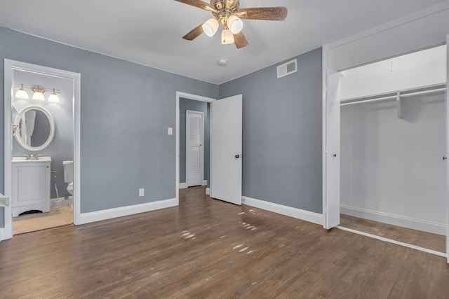 unfurnished bedroom with a closet, ceiling fan, connected bathroom, and dark hardwood / wood-style flooring