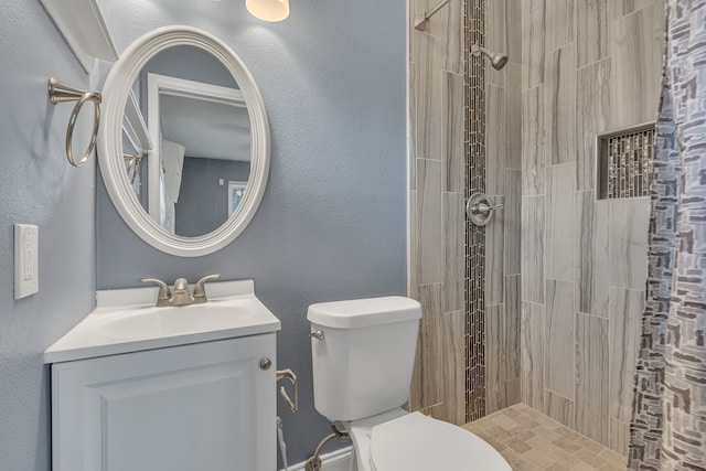 bathroom with vanity, toilet, and a tile shower