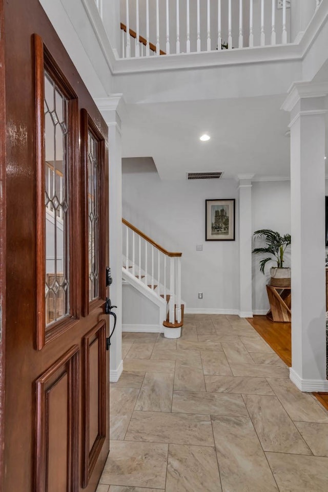 entryway with crown molding, decorative columns, and light hardwood / wood-style floors