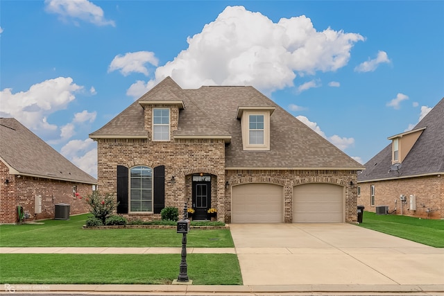 view of front of home with a garage, a front yard, and central AC unit