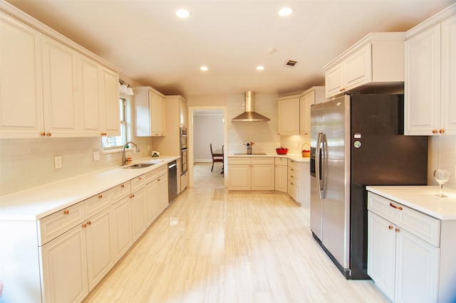 kitchen with backsplash, sink, wall chimney exhaust hood, appliances with stainless steel finishes, and white cabinets