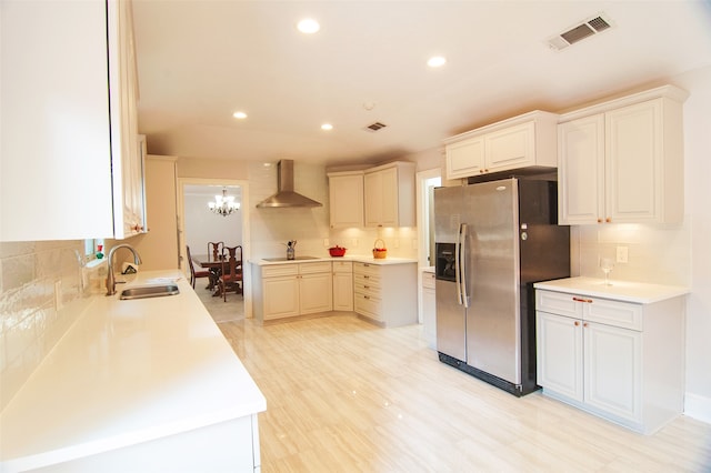 kitchen with electric stovetop, tasteful backsplash, sink, stainless steel fridge with ice dispenser, and wall chimney range hood