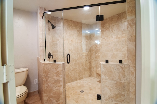 bathroom with a shower with shower door and toilet