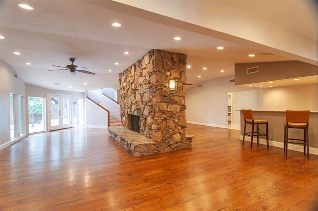 living room featuring lofted ceiling, hardwood / wood-style floors, and a fireplace