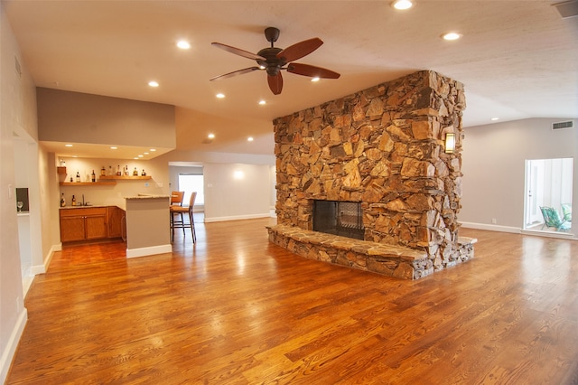 unfurnished living room with light hardwood / wood-style flooring, ceiling fan, indoor bar, and a fireplace