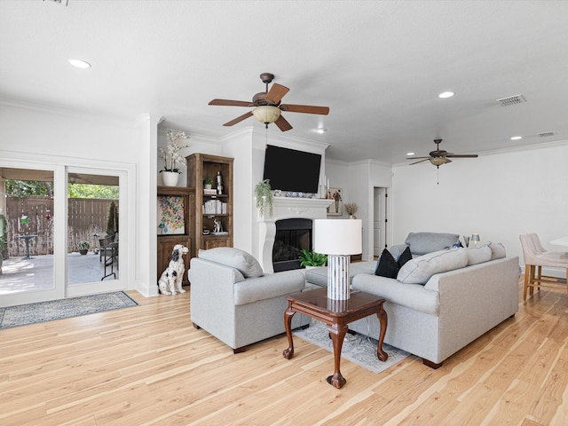 living room with ceiling fan, crown molding, and light hardwood / wood-style flooring