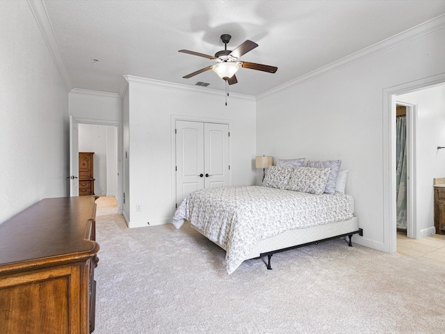 bedroom featuring ceiling fan, light colored carpet, crown molding, and a closet