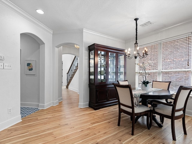 dining space featuring a textured ceiling, an inviting chandelier, crown molding, and light hardwood / wood-style flooring