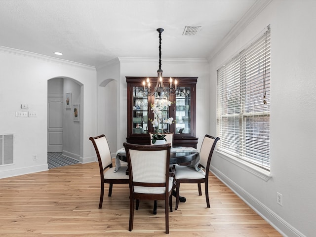 dining area featuring a chandelier, light hardwood / wood-style floors, plenty of natural light, and crown molding