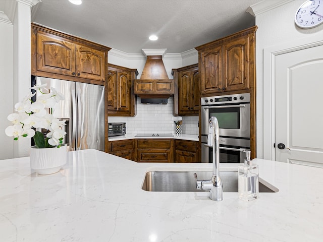 kitchen featuring backsplash, crown molding, light stone countertops, and stainless steel appliances