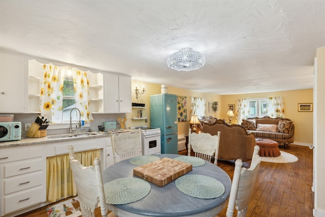 dining space with sink, wood-type flooring, and a notable chandelier