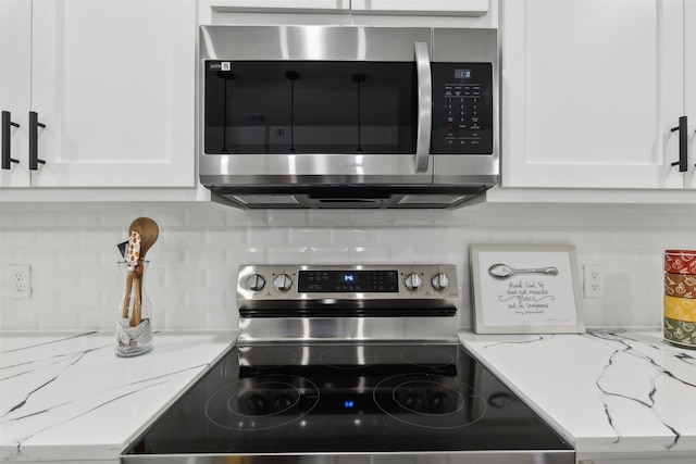 kitchen with light stone counters, white cabinetry, backsplash, and stainless steel appliances