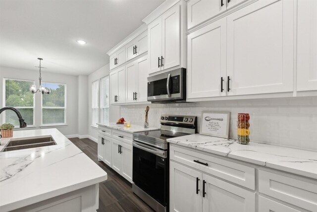 kitchen with sink, appliances with stainless steel finishes, a chandelier, and white cabinets