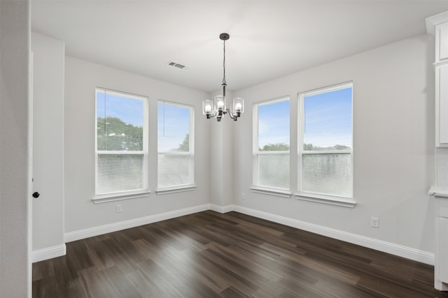 spare room with plenty of natural light, dark hardwood / wood-style floors, and a notable chandelier