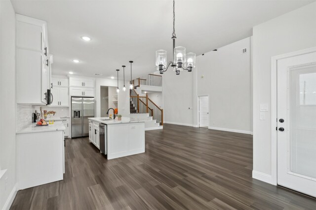 kitchen featuring appliances with stainless steel finishes, hanging light fixtures, a kitchen island with sink, and white cabinetry