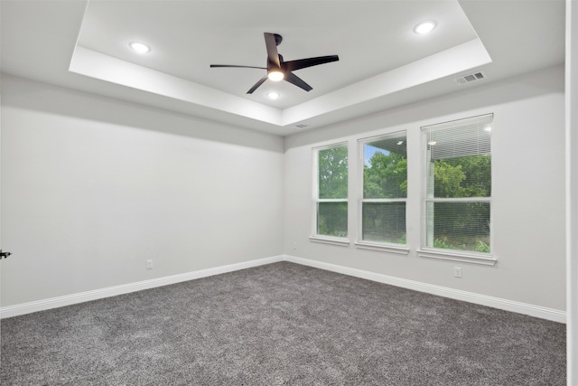 carpeted empty room with a raised ceiling and ceiling fan