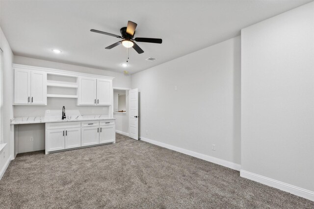 kitchen with white cabinetry, ceiling fan, and carpet floors