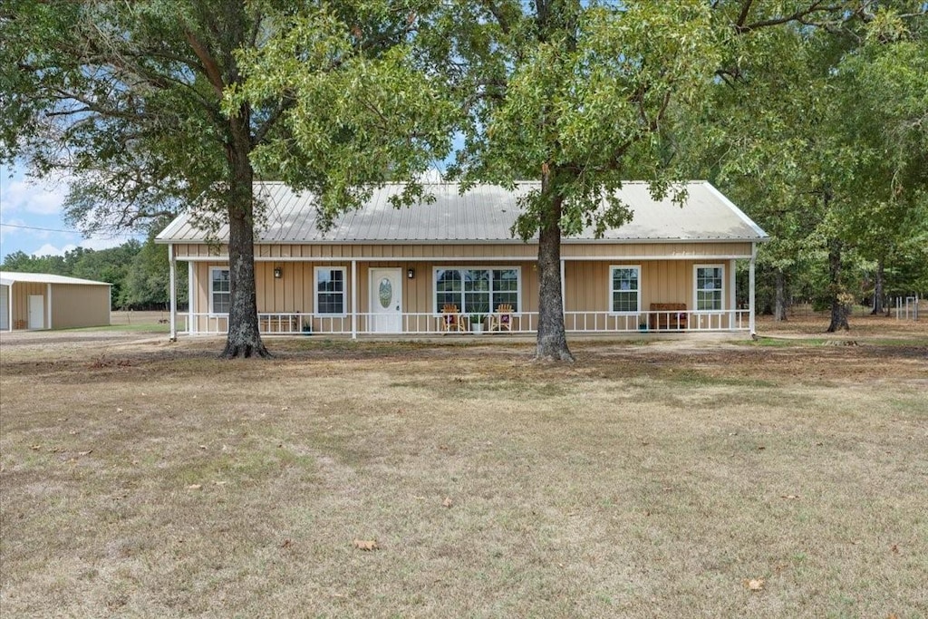 ranch-style house with covered porch, a front lawn, a garage, board and batten siding, and metal roof