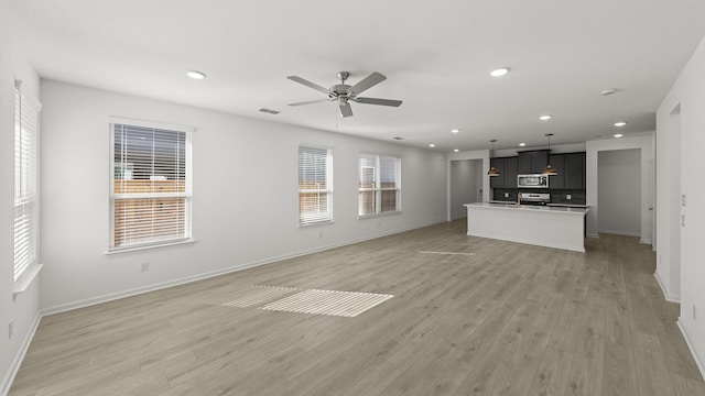 unfurnished living room with ceiling fan, a healthy amount of sunlight, and light wood-type flooring