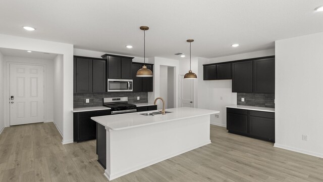 kitchen featuring sink, hanging light fixtures, light wood-type flooring, appliances with stainless steel finishes, and decorative backsplash