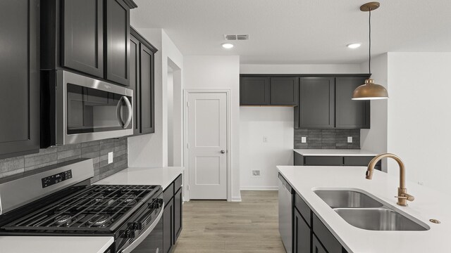 kitchen featuring tasteful backsplash, an island with sink, sink, hanging light fixtures, and stainless steel appliances