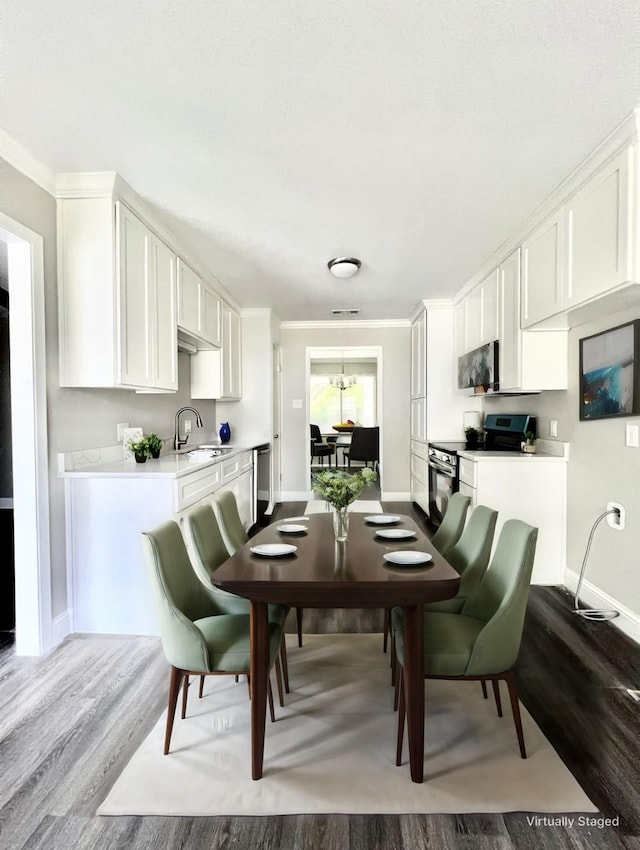 dining area featuring wood-type flooring, crown molding, and sink