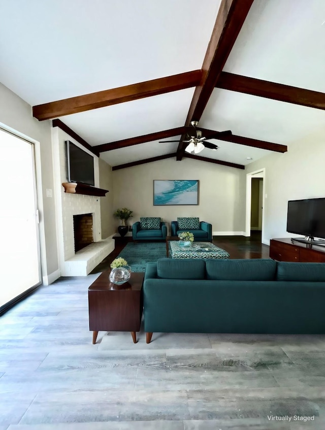 living room with a wealth of natural light, ceiling fan, a fireplace, and lofted ceiling with beams