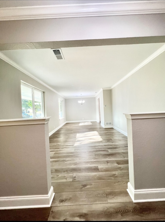 unfurnished living room featuring wood-type flooring, a notable chandelier, and ornamental molding