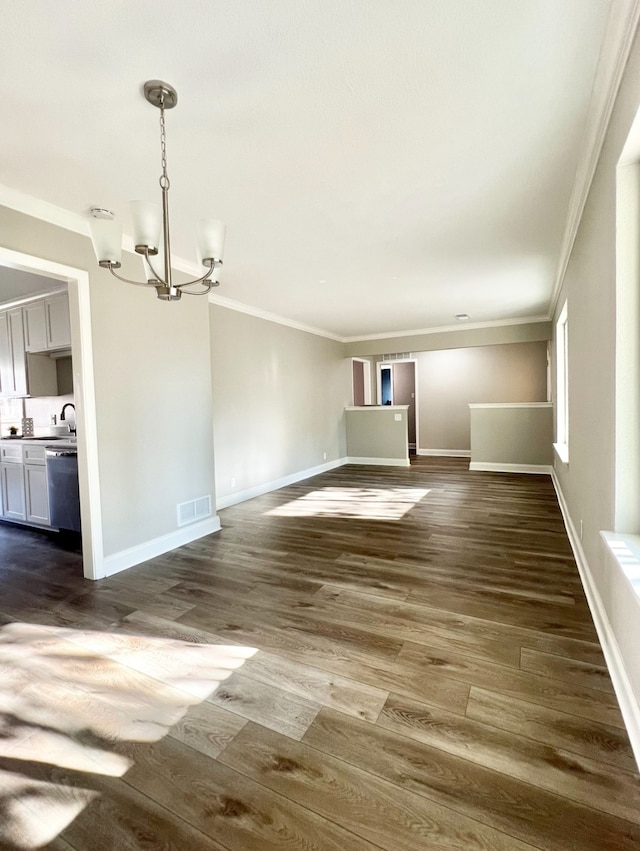 unfurnished living room featuring a chandelier, dark hardwood / wood-style flooring, crown molding, and sink