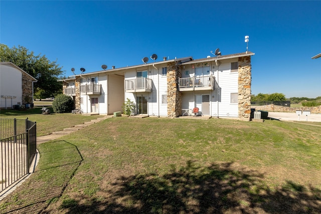 rear view of house with a balcony and a yard