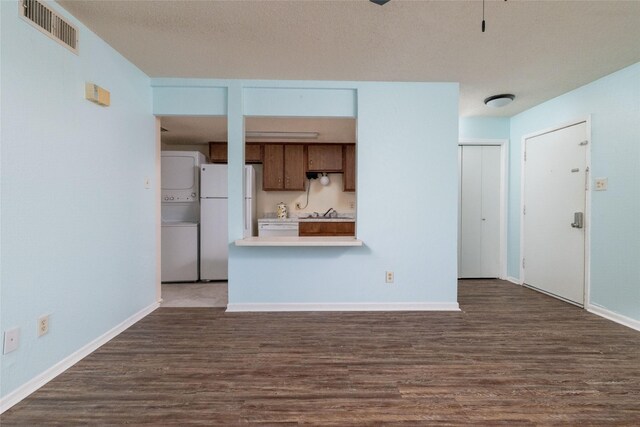 104 Harbor Dr Unit 111, Runaway Bay, TX 76426 - unfurnished living room with stacked washer / drying machine, dark wood-style floors, baseboards, and a sink