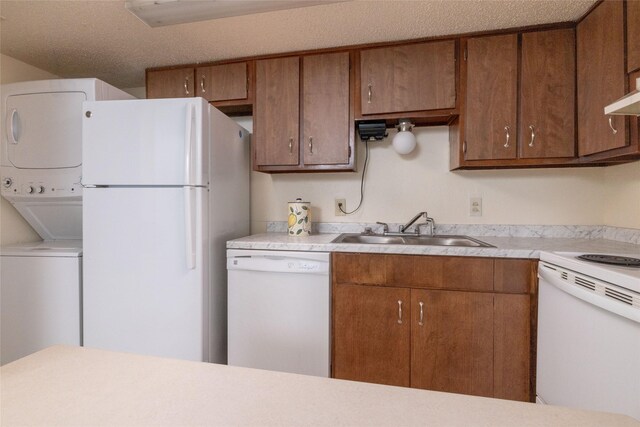 104 Harbor Dr Unit 111, Runaway Bay, TX 76426 - kitchen featuring white appliances, a sink, stacked washing machine and dryer, light countertops, and brown cabinets