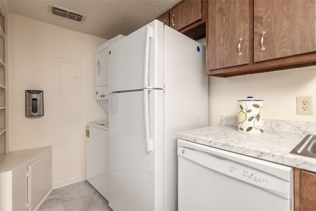 kitchen with stacked washer / dryer and white appliances