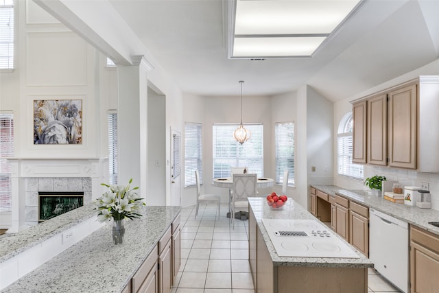 kitchen with a fireplace, white appliances, light stone countertops, light brown cabinets, and a kitchen island