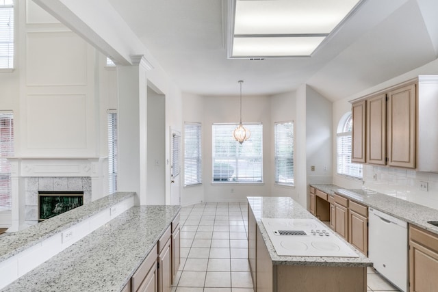 kitchen featuring a tiled fireplace, white appliances, light tile patterned floors, a kitchen island, and light stone counters