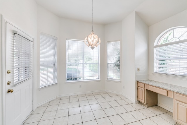 unfurnished dining area with built in desk, light tile patterned floors, a notable chandelier, and vaulted ceiling