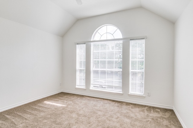 empty room with lofted ceiling, light colored carpet, and a healthy amount of sunlight