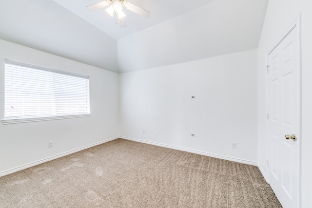 carpeted spare room featuring vaulted ceiling and ceiling fan