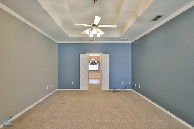 carpeted spare room featuring crown molding, ceiling fan, and a tray ceiling