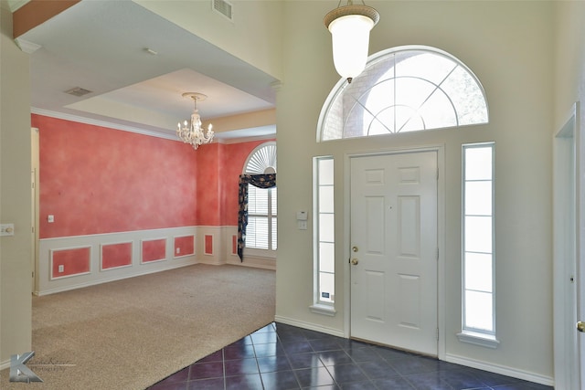 entryway featuring a high ceiling, dark colored carpet, a chandelier, and a healthy amount of sunlight