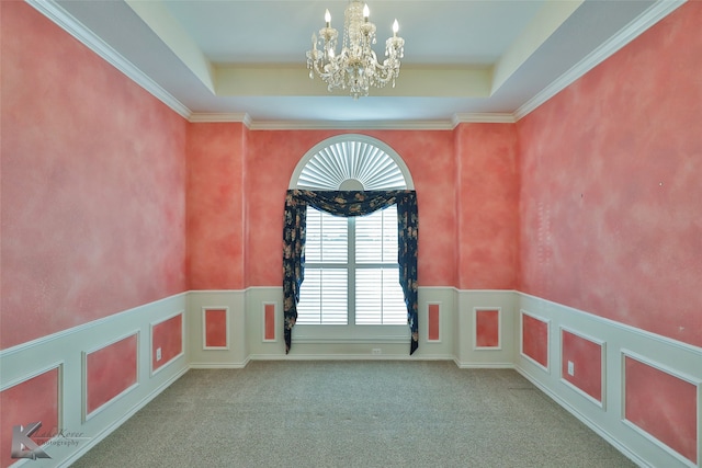 unfurnished room featuring a tray ceiling, ornamental molding, a chandelier, and carpet flooring